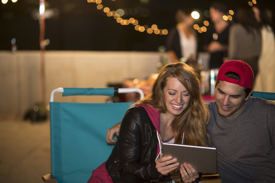 Young couple using digital tablet at rooftop barbecue
