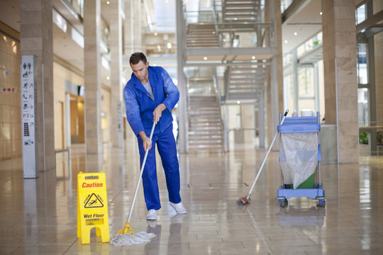 Male cleaner mopping in office atrium