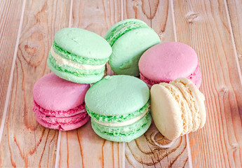 Colored sweet macaroons, french traditional, cream, close up, wood background
