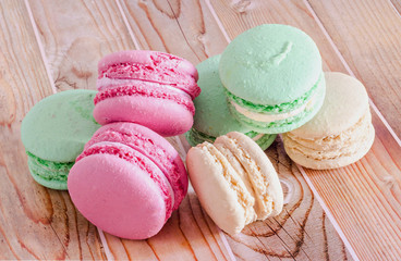 Colored sweet macaroons, french traditional, cream, close up, wood background