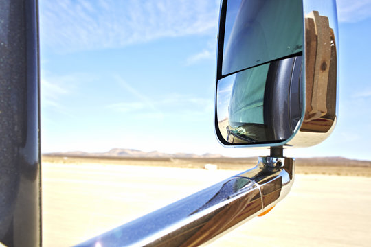 View of car wing mirror,  arid landscape and distant mountains