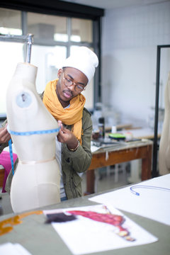 Fashion design student measuring mannequin in class