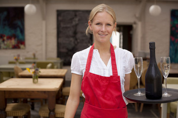 Portrait of waitress with tray of wine and glasses in cafe