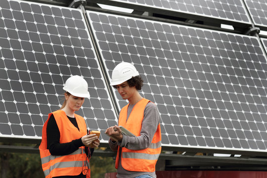Man and woman working on photo voltaic panels
