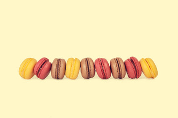 Macarons de vainilla chocolate y fresa sobre fondo amarillo vista de frente