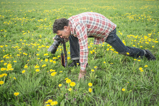 Photographer focusing closely on object in grass