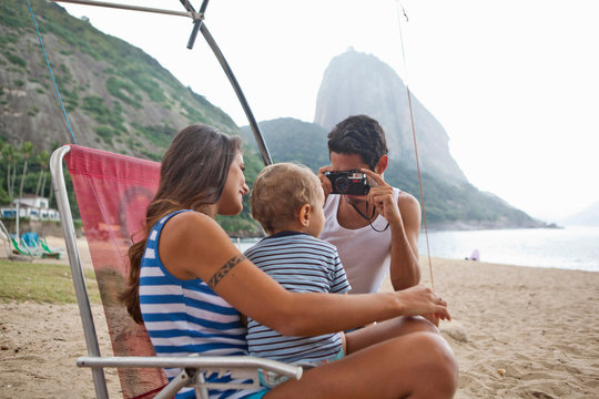 Man taking photograph of mother and son on chair, Rio de Janeiro, Brazil