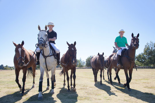 Polo players, leading horses in from field