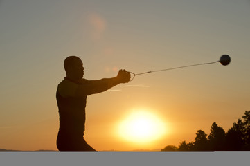 Young man preparing to throw the hammer at sunset
