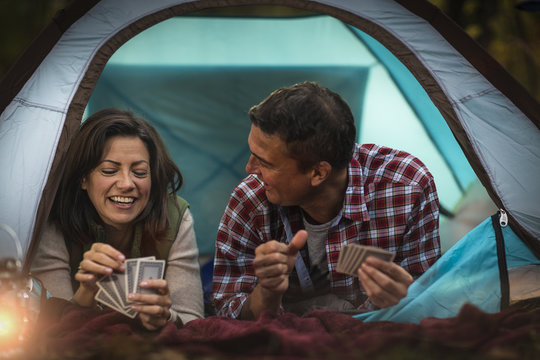 Mature couple lying together in tent, playing card game