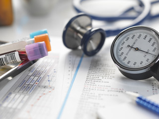 Doctors desk with patients test results, samples, stethoscope and blood pressure gauge
