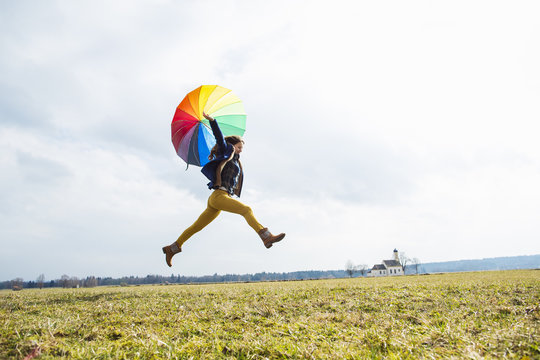 Teenage girl in field with umbrella