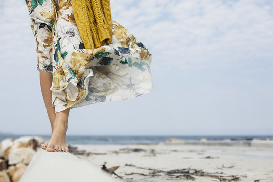 Young womans legs walking along cement block on beach, Cape Town, Western Cape, South Africa