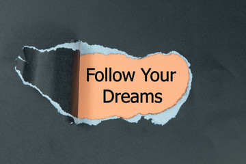 follow your dreams message written under black torn paper
