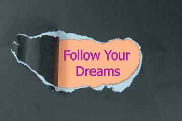 follow your dreams message written under black torn paper