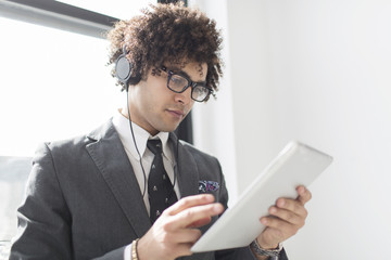Young man wearing headphones using digital tablet
