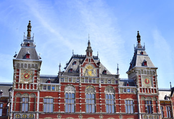Fototapeta na wymiar Amsterdam Centraal Station. Building exterior of Amsterdam Centraal and blue sky with flying seagull. Capital city of the Netherlands, central station or metro station.