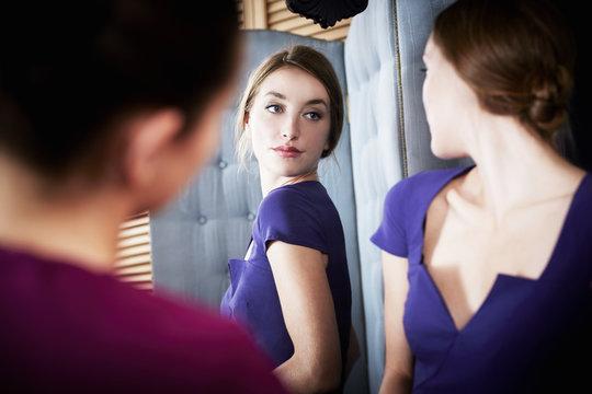 Young woman trying on dress, with friend