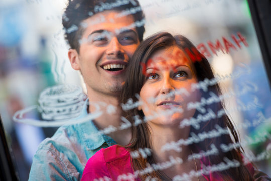 Young couple reading cafe window menu, Paris, France