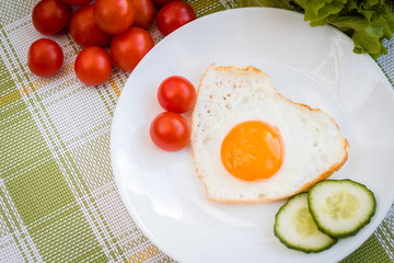 Fried egg in heart shape with vegetables