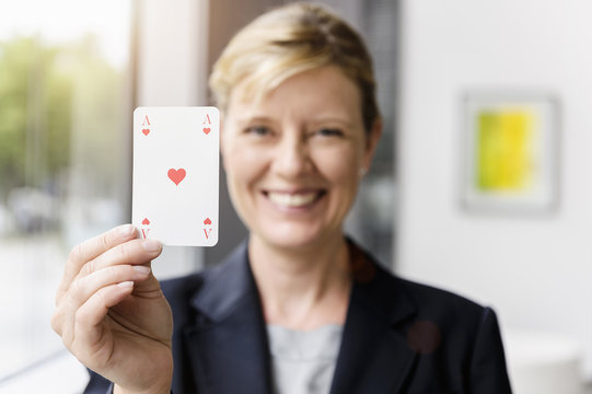 Portrait of mature businesswoman holding up ace playing card
