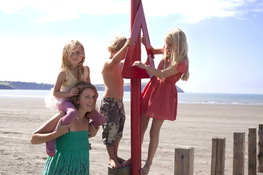 Mother with three children on beach, Wales, UK