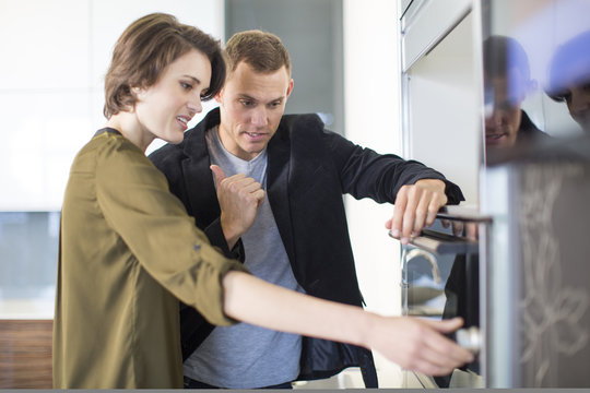 Mid adult couple inspecting oven in kitchen showroom