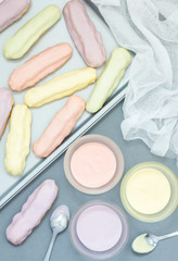 Homemade eclairs with pastel color icing on a baking sheet