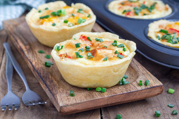 Mini quiche with chicken and bell pepper on a wooden plate