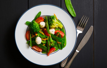 Salad with young peas, broccoli, cherry tomatoes and mozzarella