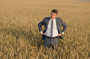 Naklejka na ściany i meble Young farmer businessman in a wheat field