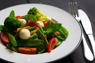 Salad with young peas, broccoli, cherry tomatoes and mozzarella
