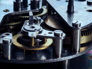 Dismantled clock mechanism. Gears of golden metal can be seen in the complex mechanism. Brass gear lie on the disassembled hours. The complex mechanism of small size. Inside the clock. 