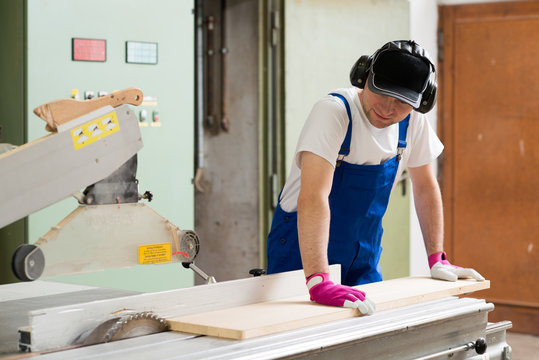 worker in workshop using saw machine