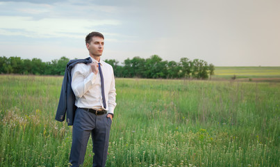 Businessman standing in field and looking forward