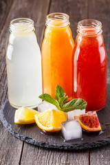Fresh citrus juices on a dark wooden background.