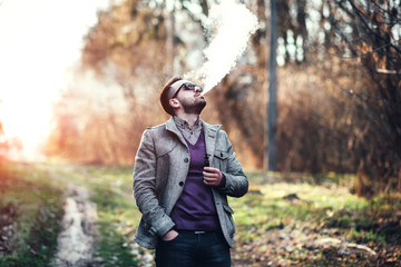 Man with beard vaping outdoor electronic sigarette