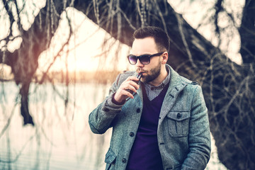 Man with beard  vaping outdoor electronic sigarette