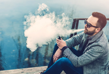 Man with beard  vaping outdoor electronic sigarette