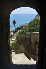 Arched doorway on steep walkway in Positano, Italy, with the Mediterranean Sea below.