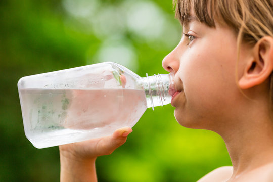 Girl drinking clean tap water from transparent plastic bottle