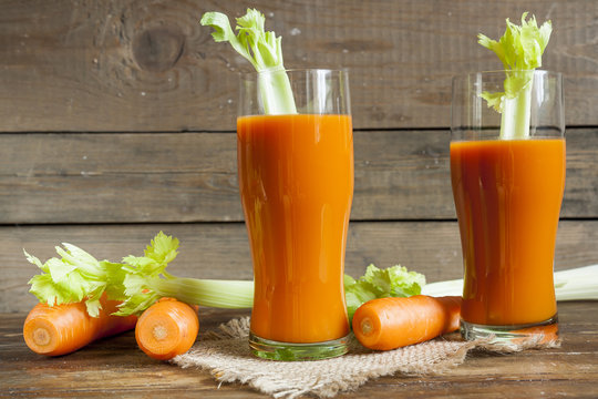 Fresh carrot juice with carrots and celery on dark wooden background
