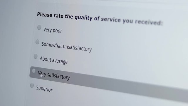 Macro shot of a mouse cursor on a monitor indicating a person giving a good or satisfactory service review on a computer based internet business customer satisfaction survey.