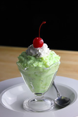 Watergate salad topped with whipped cream and a cherry on top