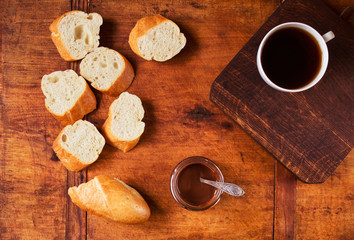 Fototapeta na wymiar Fresh French baguette with chocolate and coffee for breakfast on dark wooden table, top view