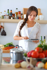 Young woman using a tablet computer to cook in her kitchen