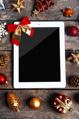 Tablet and Christmas decor on wooden background