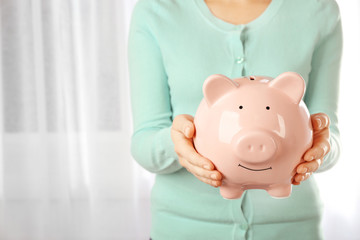 Woman holding piggy bank in hand. Financial savings concept