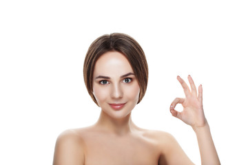 Obraz na płótnie Canvas Pretty girl with natural makeup show gesture OKEY. Beautiful spa woman touching her face. Perfect fresh skin. Pure beauty model girl. Youth and skin care concept