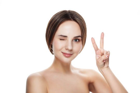 Pretty girl with natural makeup show gesture VICTORY. Beautiful spa woman touching her face. Perfect fresh skin. Pure beauty model girl. Youth and skin care concept